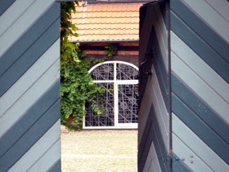 Portal führt in einen Innenhof mit Buntglasfenster – Abtei St. Scholastika, Dinklage