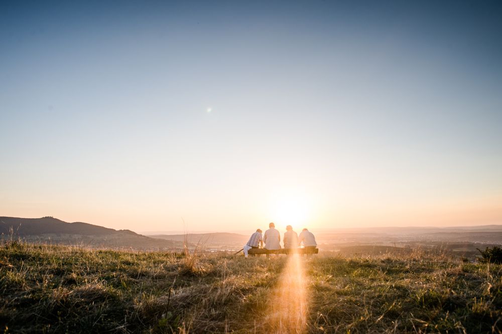 Vier Personen auf einer Bank im Sonnenaufgang